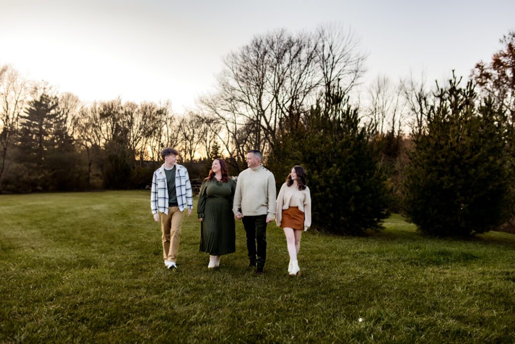 Family picking out their Christmas tree at a picturesque tree farm, with rows of evergreen trees.